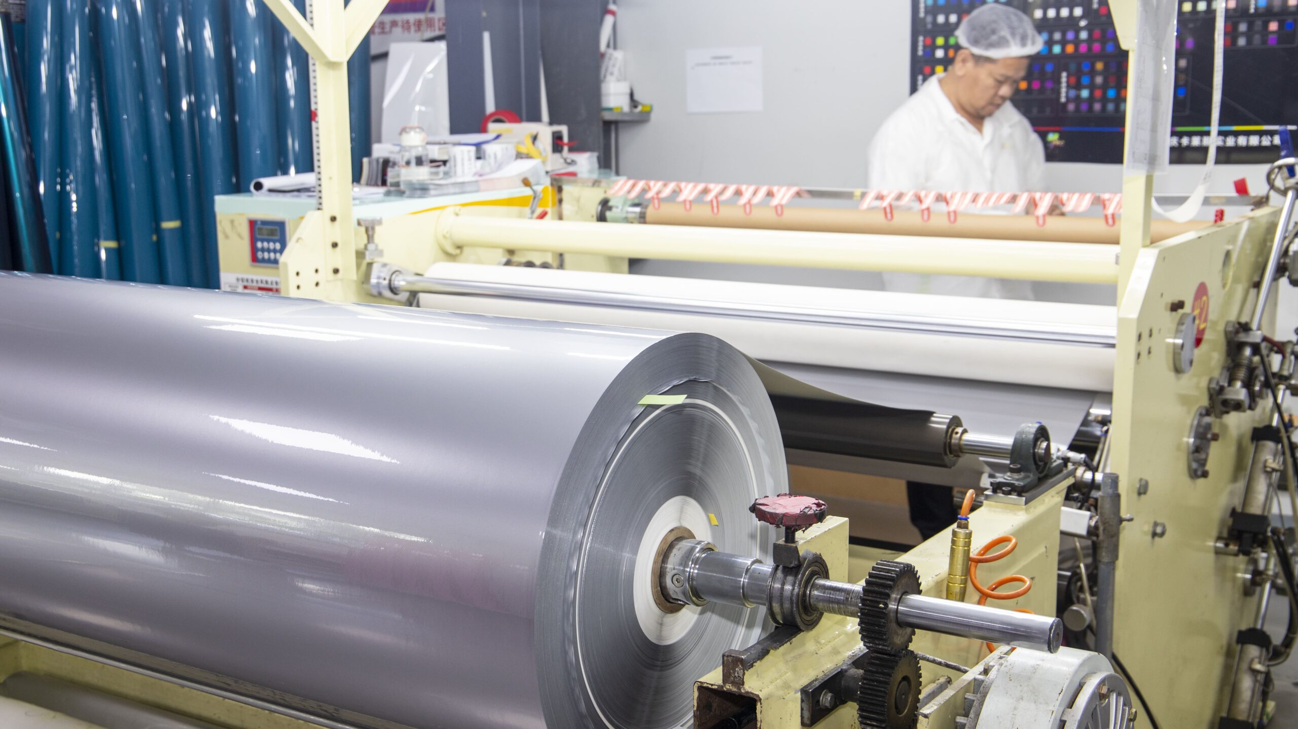 A wide shot of a modern, organized factory floor with large film production machinery